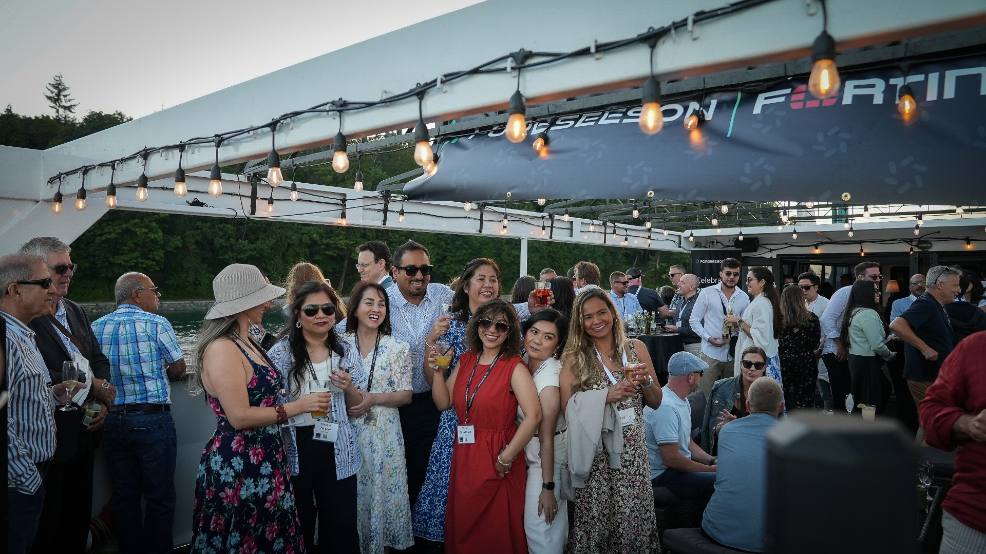 Guests gathered on the cruise deck under string lights at sunset