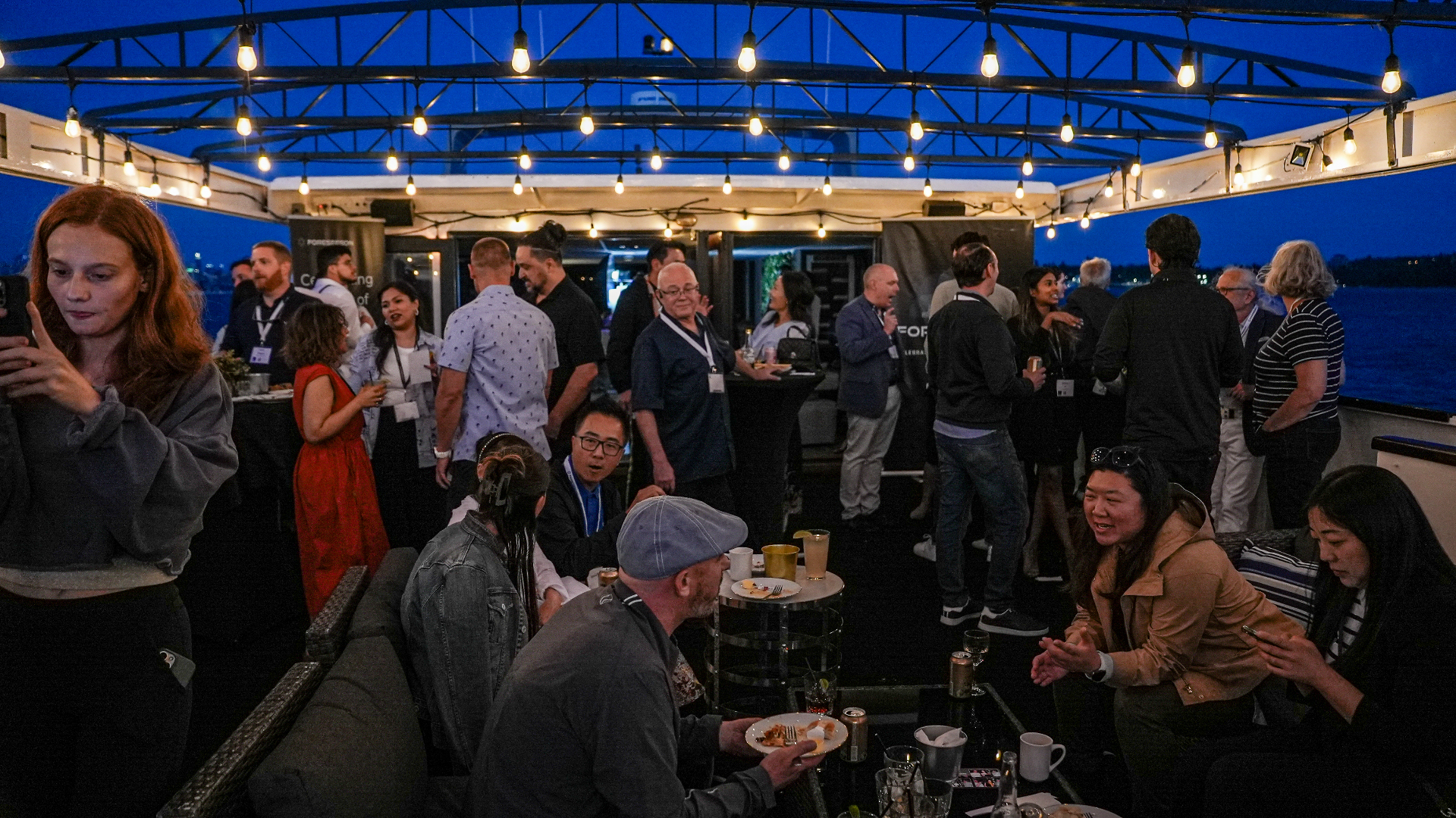Guests mingling on the deck under string lights at blue hour
