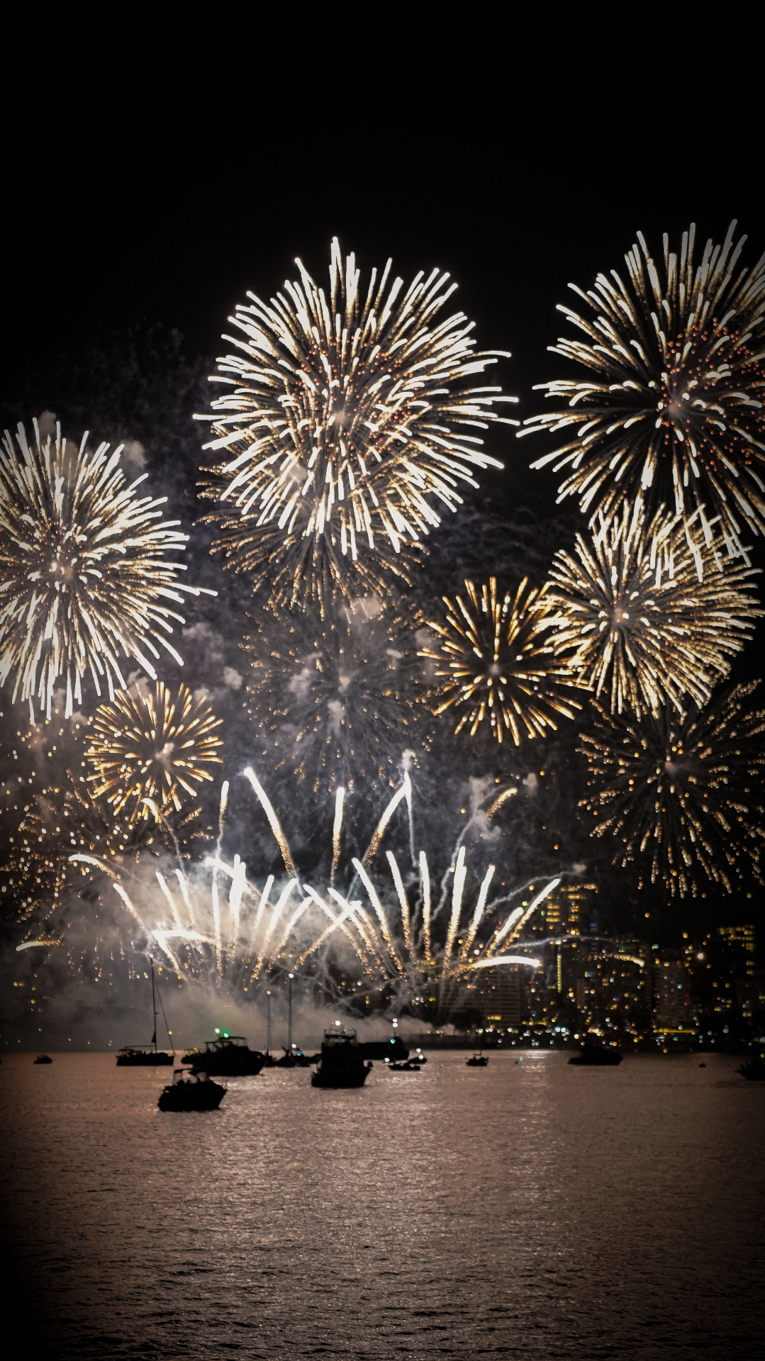 Gold fireworks bursting over Vancouver's waterfront with boats below